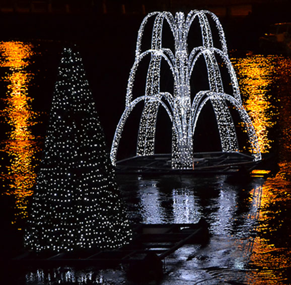 Décorations de noël illuminées en blanc de type sapin sur des planches sur l'eau